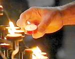 picture of somebody lighting  candle as they pray 